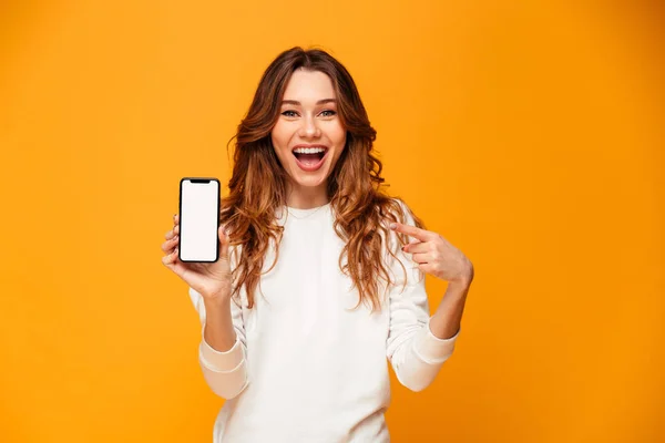 Glad brunett kvinna i tröja visar tom smartphone skärmen — Stockfoto