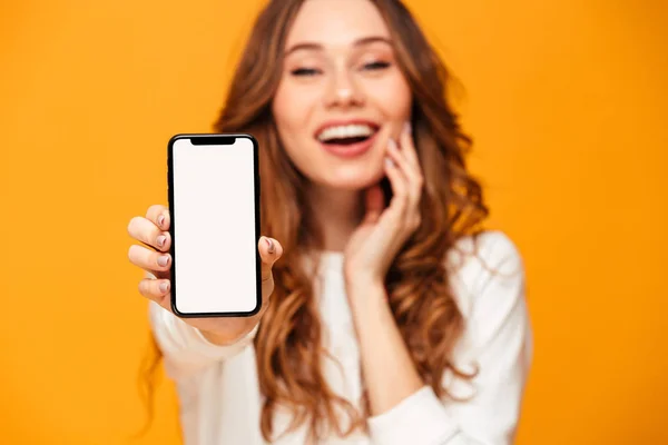 Glada brunett kvinna i tröja visar tom smartphone rasbranter — Stockfoto