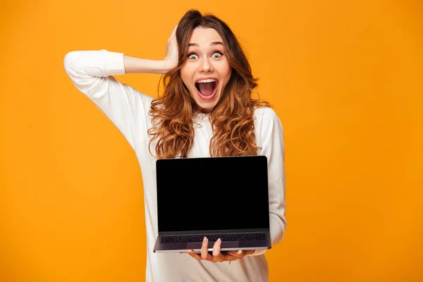 Shocked happy brunette woman in sweater showing blank laptop screen
