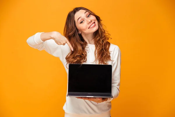 Glada brunett kvinna i tröja visar tom laptop datorskärm — Stockfoto