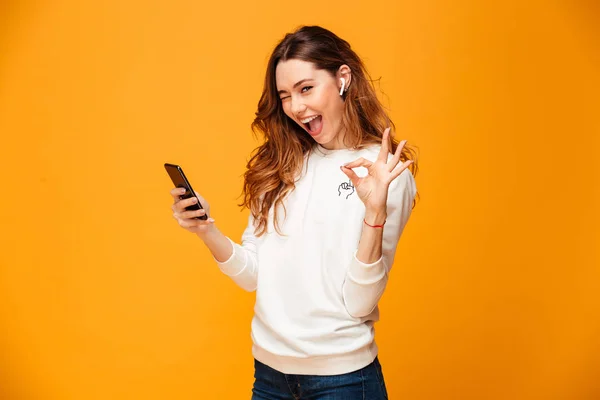 Mujer morena alegre en suéter sosteniendo teléfono inteligente — Foto de Stock