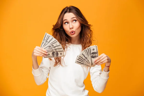 Pleased brunette woman in sweater holding money and waving them — Stock Photo, Image