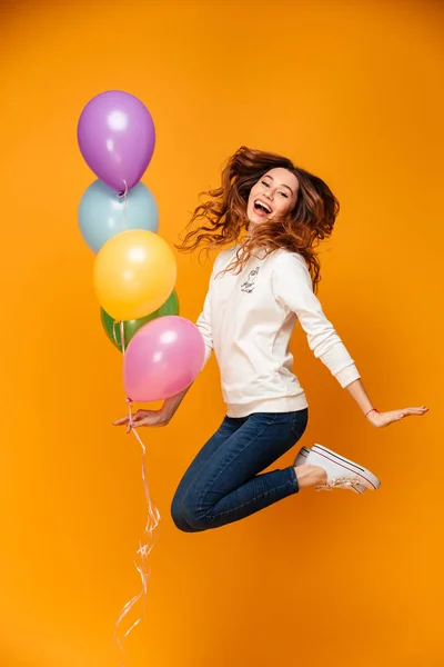 Excited young woman jumping isolated holding balloons.