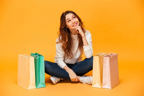 Nadenkend blij brunette vrouw in trui zittend op de vloer — Stockfoto