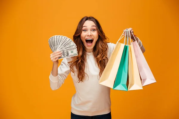 Emocionado gritando joven dama sosteniendo bolsas de compras y dinero . — Foto de Stock