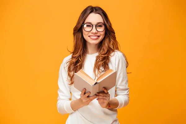Mosolygós barna nő-ban pulóver és a szemüveget tartó könyv — Stock Fotó