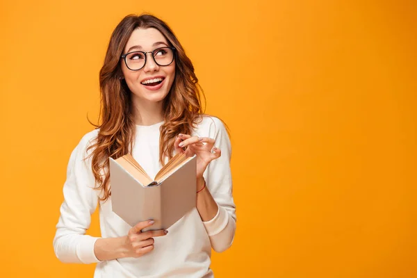 Mujer morena sonriente pensativa en jersey y gafas con libro — Foto de Stock