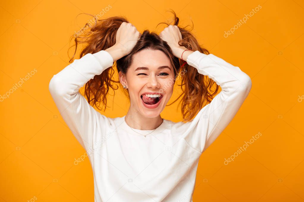 Cheerful brunette woman in sweater holding her hair