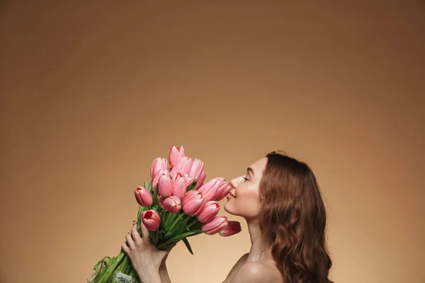 Красивая молодая женщина стоит в одиночестве, держа тюльпаны — стоковое фото