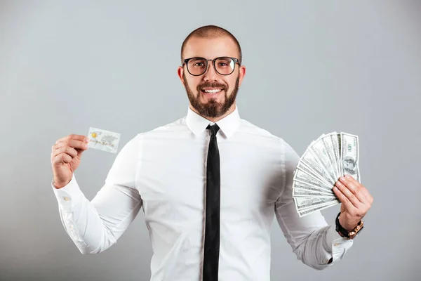 Foto de hombre rico de 30 años en gafas y corbata mostrando tarjeta de crédito y — Foto de Stock