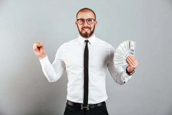 Foto de hombre rico 30s en gafas y traje mostrando bitcoin y lo — Foto de Stock