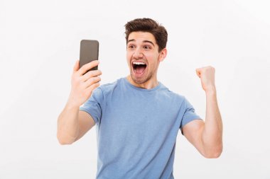 Çığlık neşeli t-shirt holding smartphone içinde adam ve sevinir