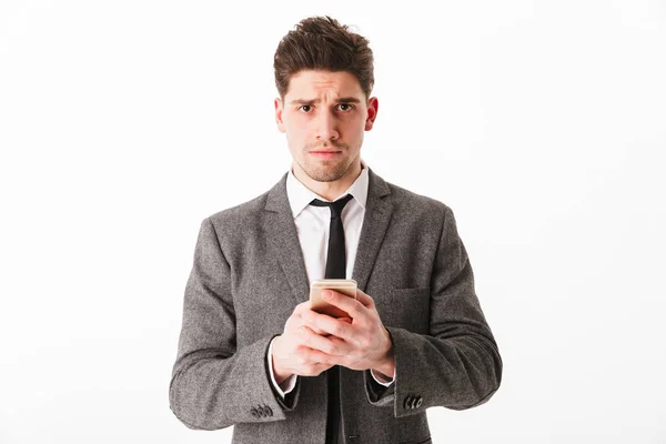 Retrato de un joven empresario molesto sosteniendo el teléfono móvil — Foto de Stock