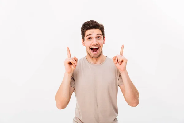 Удивленный брюнетка мужчина 30 лет в бежевой футболке жестом пальца — стоковое фото