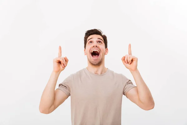 Jeune homme en t-shirt décontracté regardant vers le haut avec le doigt pointant — Photo