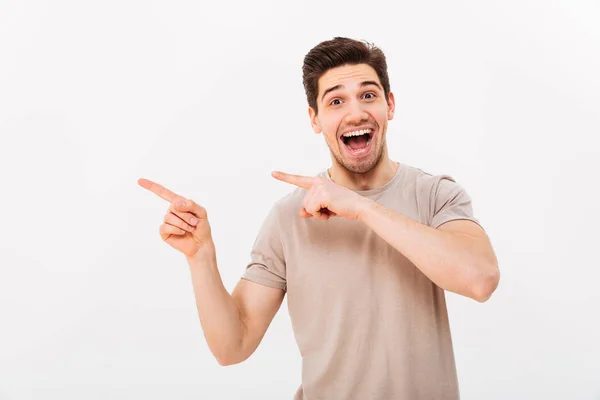 Aufgeregter Mann im lässigen T-Shirt jubelt und zeigt mit dem Finger. — Stockfoto