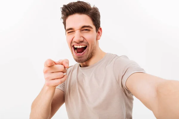 Радостный мужчина с каштановыми волосами жестикулирует указательным пальцем на камеру — стоковое фото
