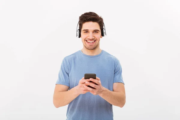 Nieogolony mężczyzna w casual t-shirt słuchać muzyki poprzez bezprzewodowe e — Zdjęcie stockowe