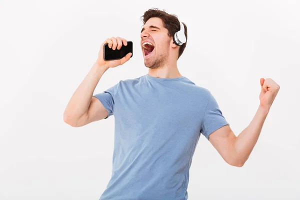 Glad ung man 30s i casual t-shirt Lyssna på musik via wi — Stockfoto