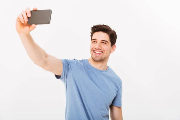 Hombre alegre con el pelo castaño sonriendo en la cámara mientras toma selfie — Foto de Stock