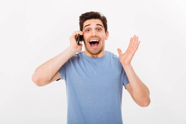 Sorprendido hombre feliz en camiseta hablando por teléfono inteligente — Foto de Stock