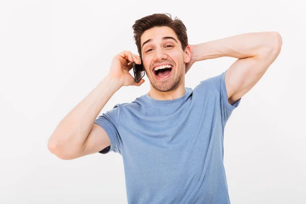 Lachender Mann im T-Shirt, der mit dem Smartphone spricht und dabei den Kopf schüttelt — Stockfoto