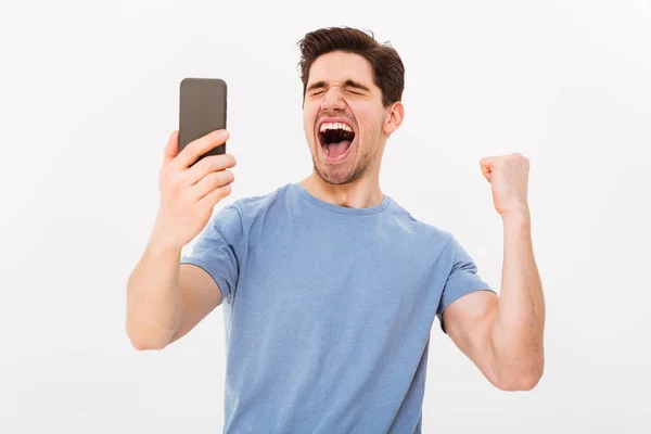 Щасливий кричущий чоловік у футболці тримає смартфон — стокове фото