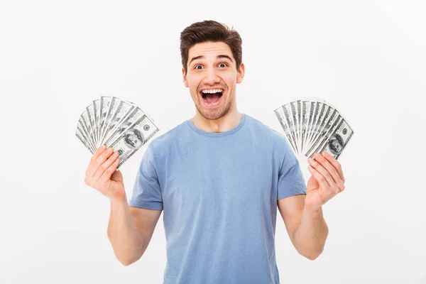Young rich man in casual t-shirt holding two fans of money dolla — Stock Photo, Image