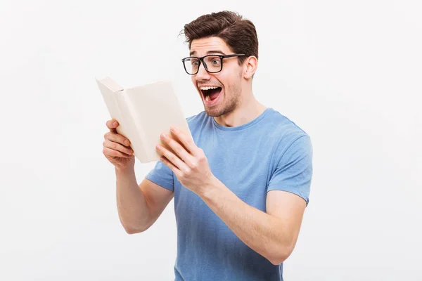 Happy screaming nerd in eyeglasses and t-shirt reading book — Stock Photo, Image