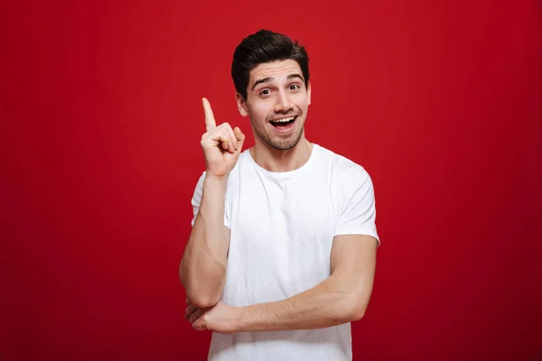 Porträtt av en glad ung man i vit t-shirt pekar — Stockfoto