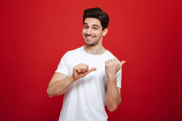 Retrato de un joven feliz en camiseta blanca señalando — Foto de Stock