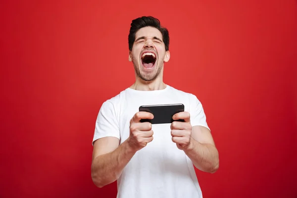 Portret van een tevreden jonge man in het witte t-shirt vieren — Stockfoto