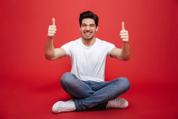 Retrato de um jovem alegre em t-shirt branca sentado — Fotografia de Stock