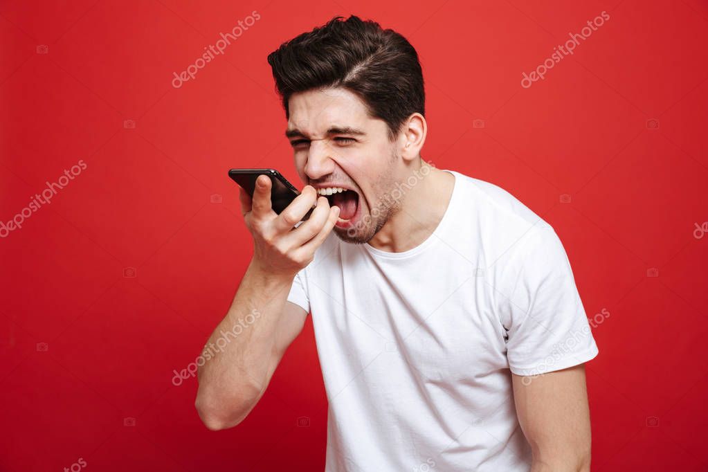 Portrait of an angry young man in white t-shirt yelling