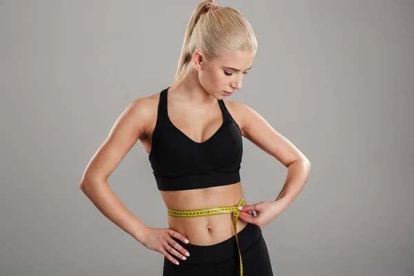 Portrait of a slim young sportsgirl holding measuring tape — Stock Photo, Image