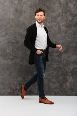 Yakışıklı genç işadamı gri duvardan yürüyüş