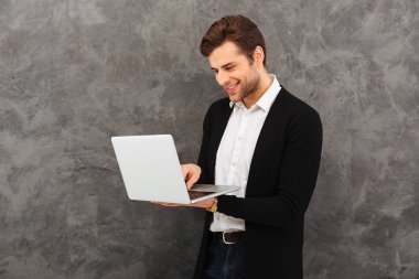 Dizüstü bilgisayar kullanan neşeli işadamı.