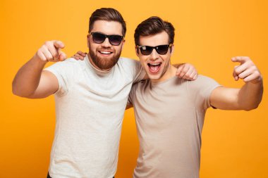 Rahat t-shirt ve sarılma güneş gözlüğü ve poin iki mutlu erkeklerde