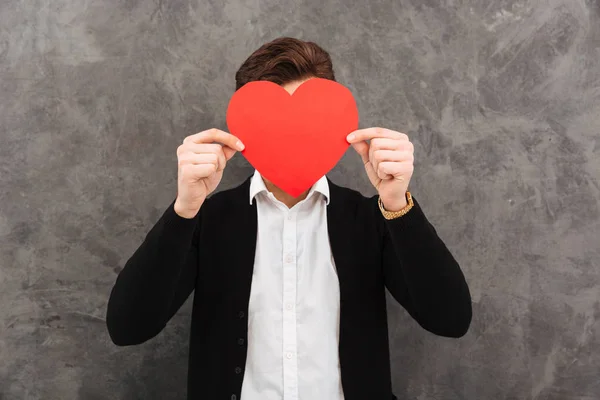 Businessman standing covering face holding heart. — Stock Photo, Image