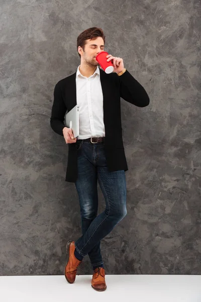 Jonge zakenman holding laptopcomputer koffie drinken. — Stockfoto