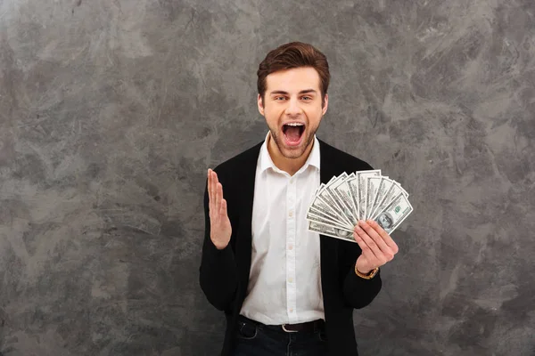 Emocionado joven empresario feliz sosteniendo el dinero mirando cámara . — Foto de Stock