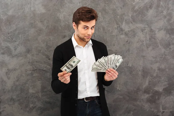 Jovem empresário alegre segurando dinheiro olhando câmera . — Fotografia de Stock