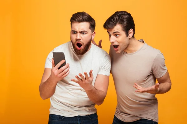 Photo of two men football fans emotionally gesturing while watch