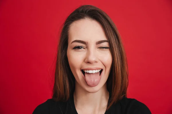 Foto de primer plano de la mujer alegre de 20 años con el pelo castaño largo guiñando un ojo —  Fotos de Stock