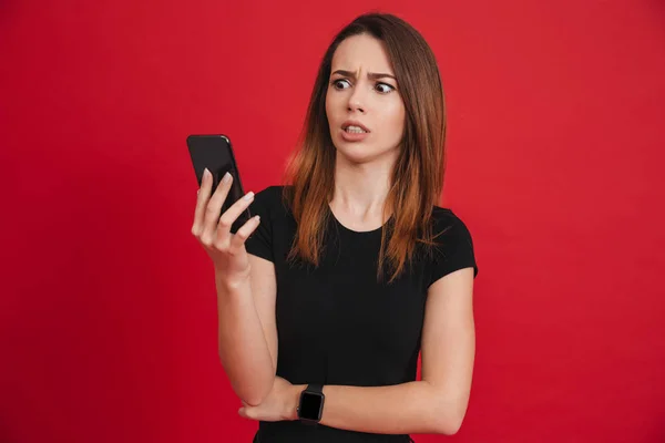 Foto einer unzufriedenen Frau in schwarzer Kleidung, die auf ihr Handy schaut — Stockfoto