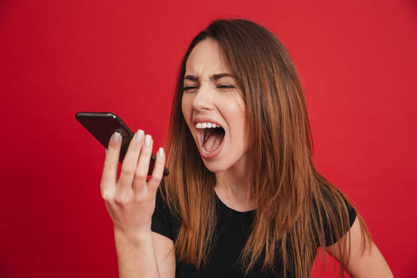 Photo of furious brunette woman screaming on phone while having 
