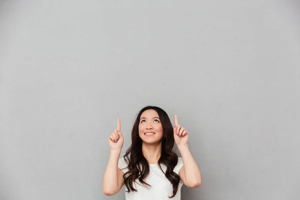Изображение очаровательной приветливой женщины в повседневной футболке, указывающей пальцем — стоковое фото