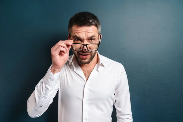 Uomo confuso indossando occhiali in piedi su sfondo scuro — Foto Stock