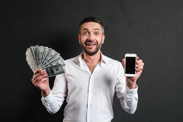 お金を入れる携帯電話のディスプレイを示す幸せなビジネスマン. — ストック写真