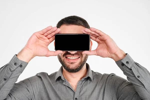 Smiling man covering eyes with phone. — Stock Photo, Image